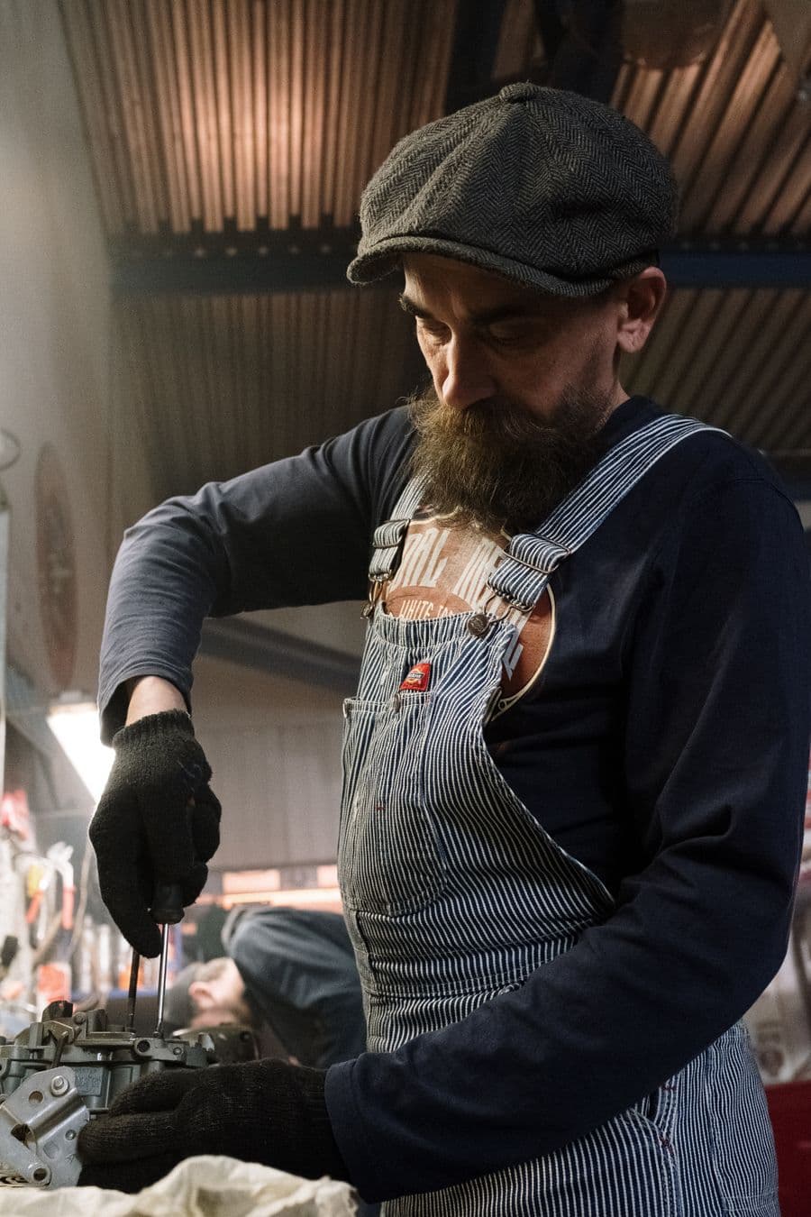 Mechanic in overalls repairing an engine in a workshop